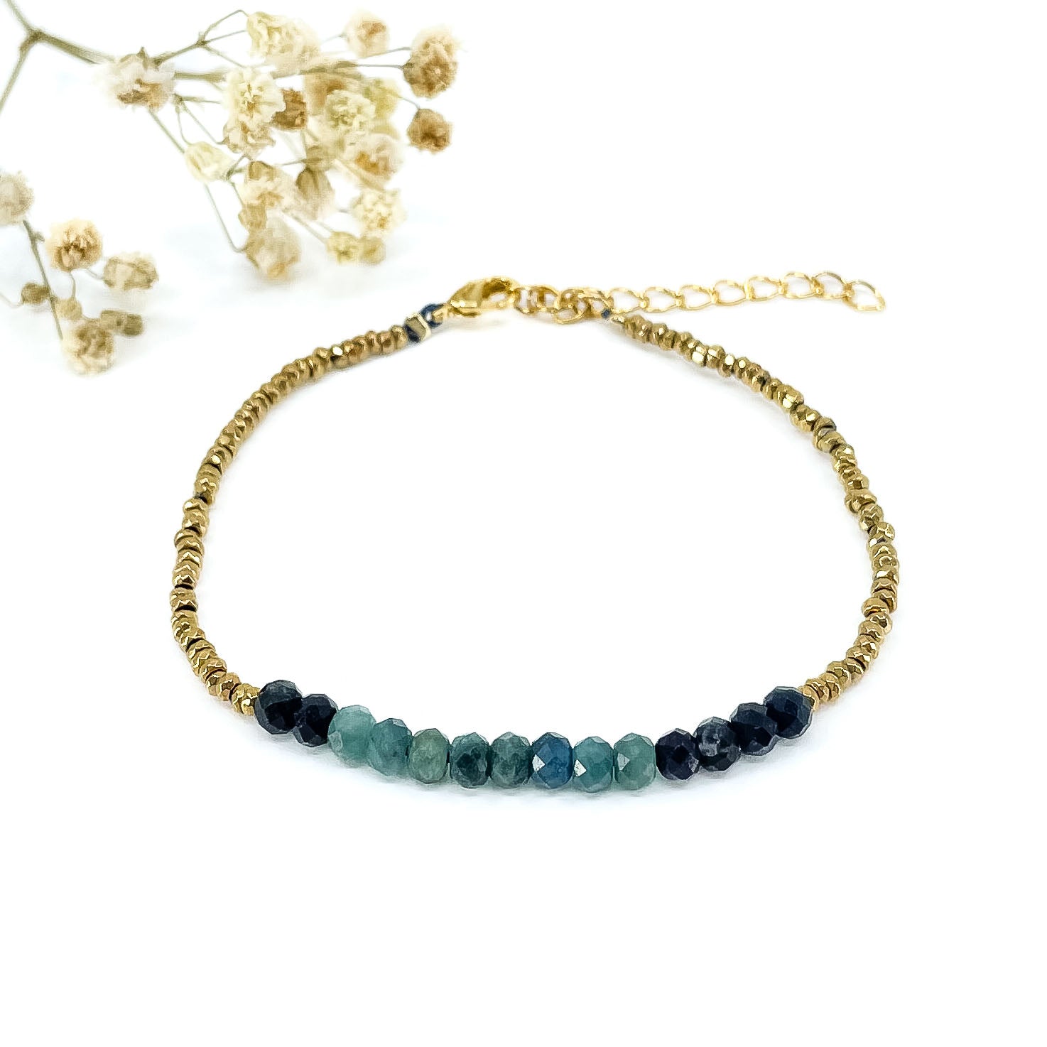 Bracelet en perles de pierres fines naturelles de Tourmaline bleu-vert intense. Elle sont encadrées de perles d'Hématites dorées.