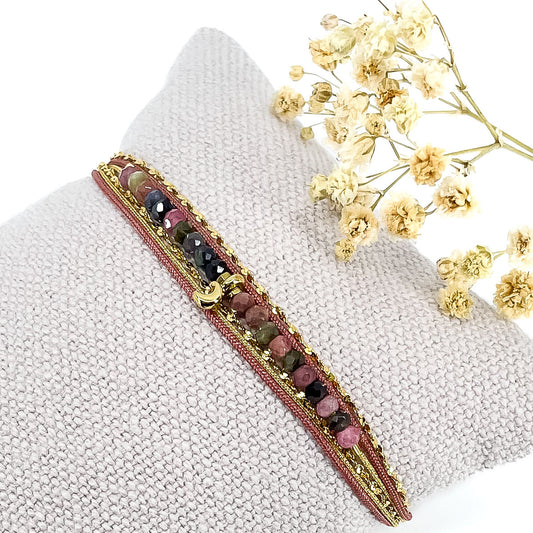 Bracelet composés de plusieurs liens cordons et chaine doré et rose s'enroulant autour du poignet. Sur un cordon des perles de pierre naturelle de tourmalines multicolores sont ponctuées par un pendentif croissant de lune doré.