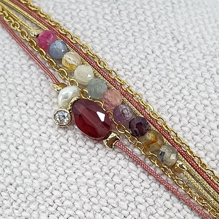 Bracelet composé de 3 liens cordons et chaîne s'enroulant en deux tours sur le poignet. Il met en valeur les perles de pierre naturelle de Tourmaline ainsi qu'un Grenat, une Perle de Culture et un petit pendentif serti d'un cristal. Pierres et perles sont montées sur les différents liens.