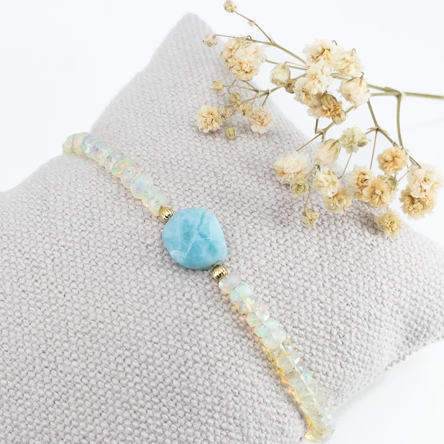 Bracelet en pierres fines naturelles composé d'une pierre facettée de Larimar en forme de galet bleu clair, entouré d'une longue rivière d'Opales aux mille reflets iridescents