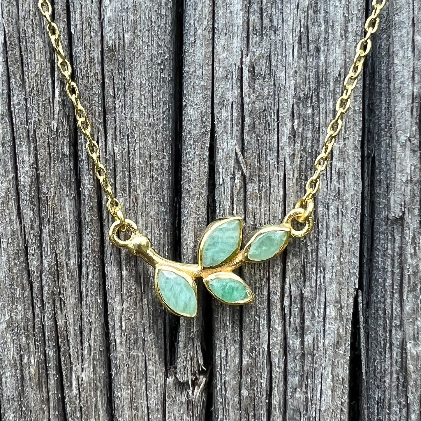 Collier plaqué or avec chaîne ajustable sur 3 niveaux de longueur différentes de 37 à 45 cm. Il met en valeur une brindille de feuillage réalisée en pierres fines naturelles d'Amazonite vert lagon