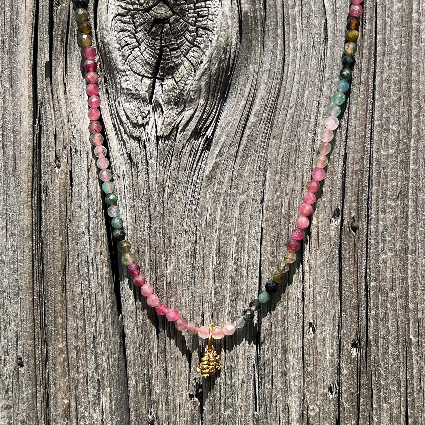 Collier rivière de perles de pierres fines naturelles de Tourmaline teinte arc-en-ciel. Pendentif composé de petites pierres d'hématite dorée. Chaîne de fermeture ajustable de 39 à 44 cm.