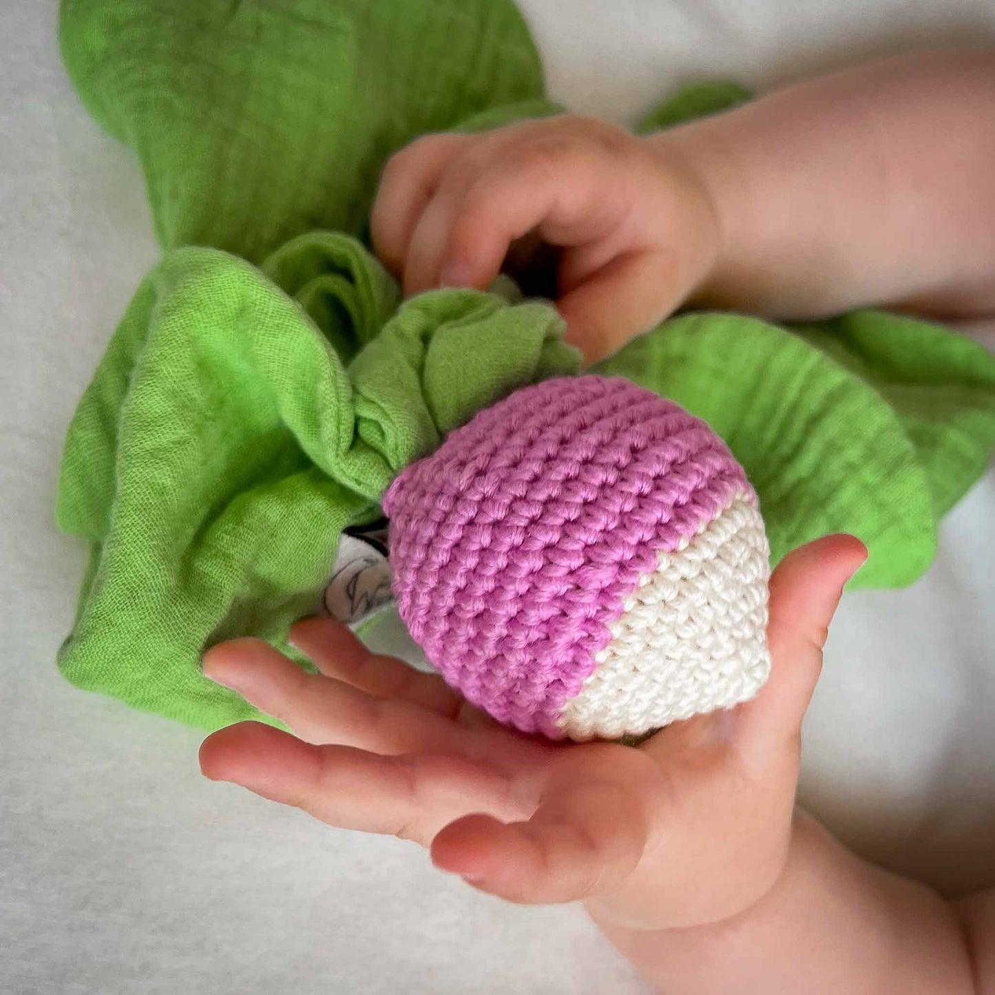 Doudou pour bébé radis rond blanc et mauve, feuilles vertes, en coton biologique certifié GOTS et crochet fait à la main.