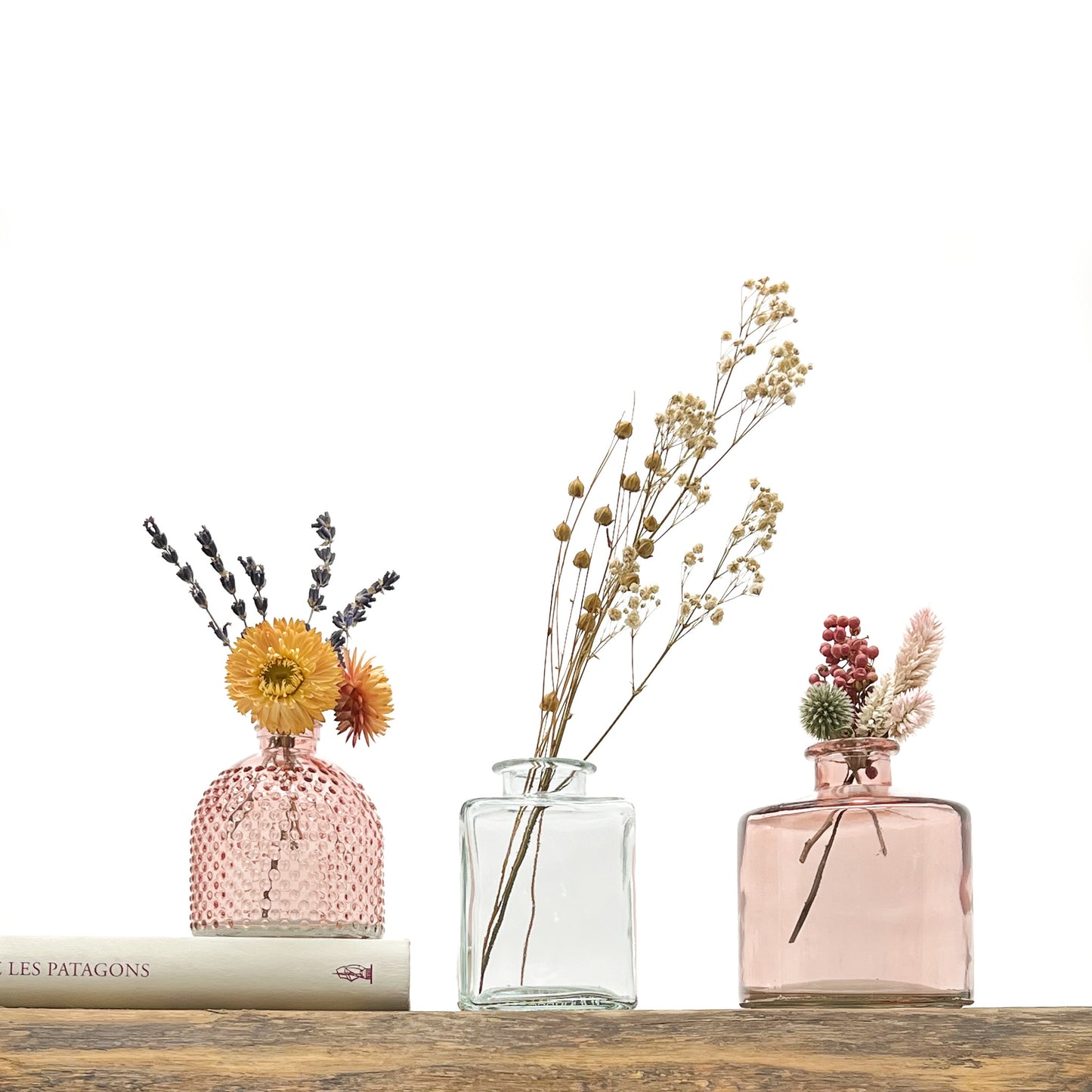 Ensemble de 3 vases en verre, deux dans les tons rosé, le troisième translucide. Design différencié et harmonieux. Livrés avec fleurs séchées offertes.